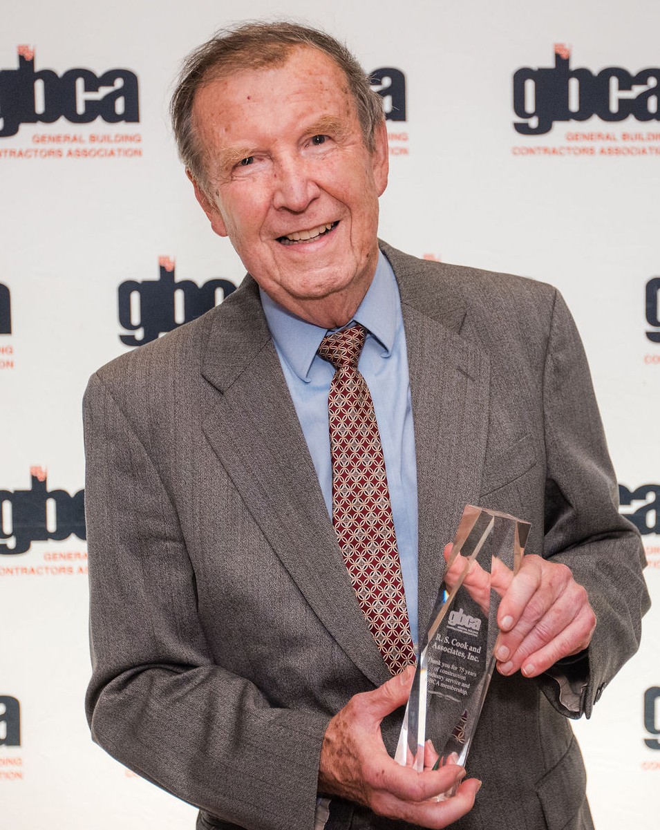 headshot of man in suit with award